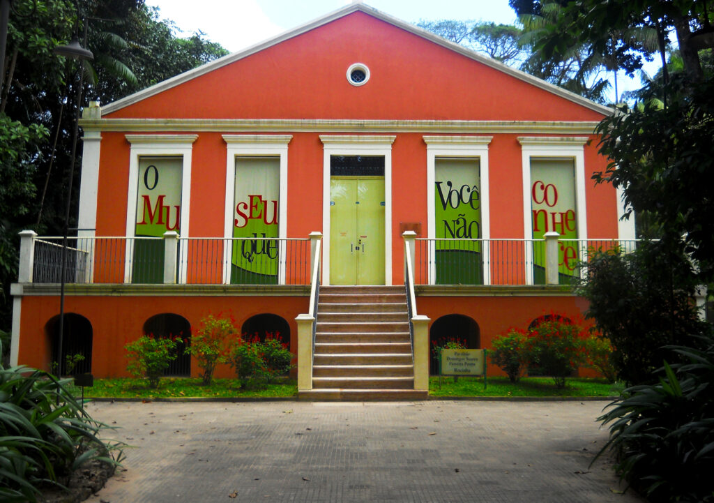 foto da faixada do museu. Paredes laranjas, intercaladas com grandes portas