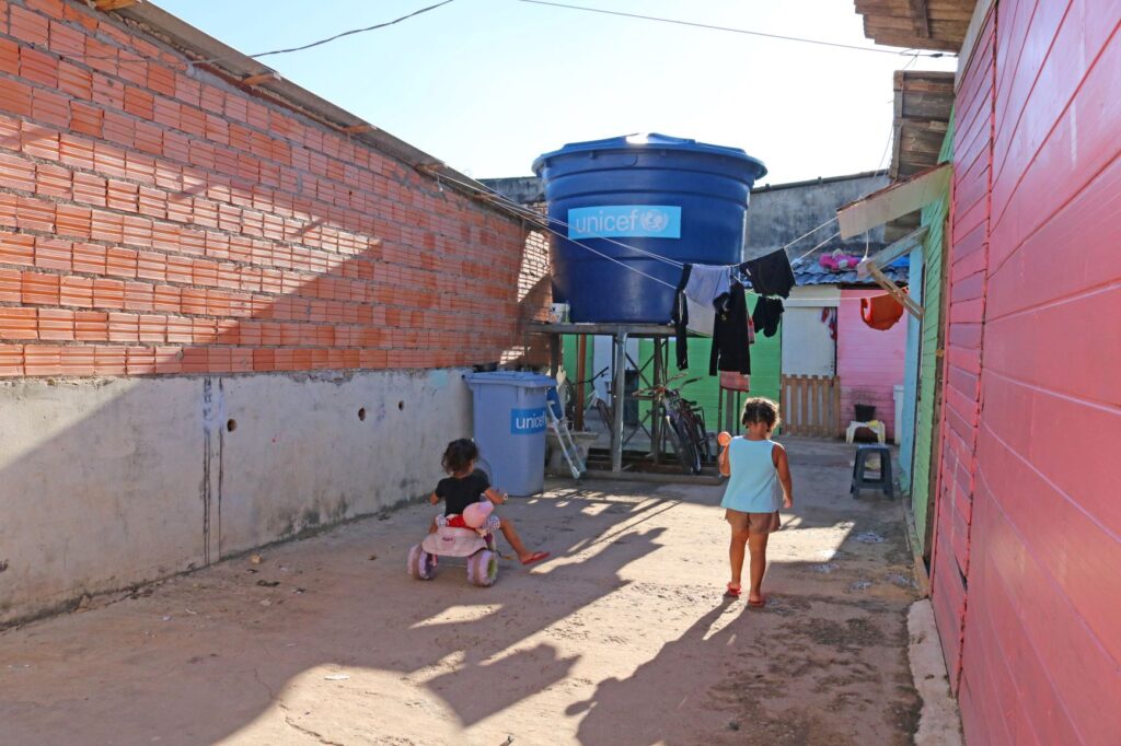 Duas crianças brincam em uma área com construções de tijolos expostos