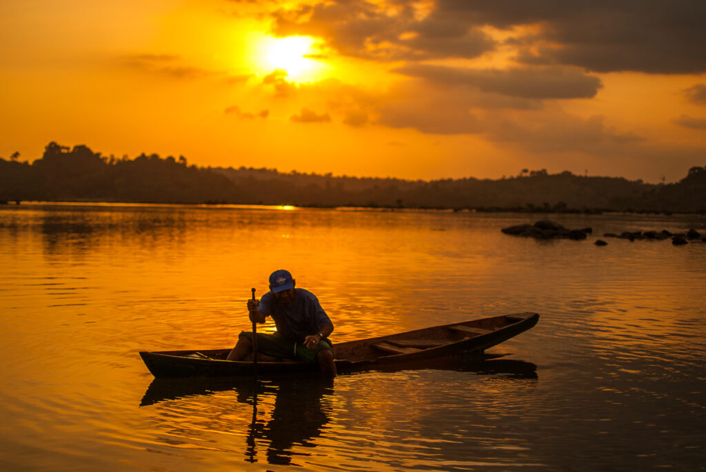 Uma canoa no Xingu. Ao fundo, o por do sol que deixa a paisagem dourada
