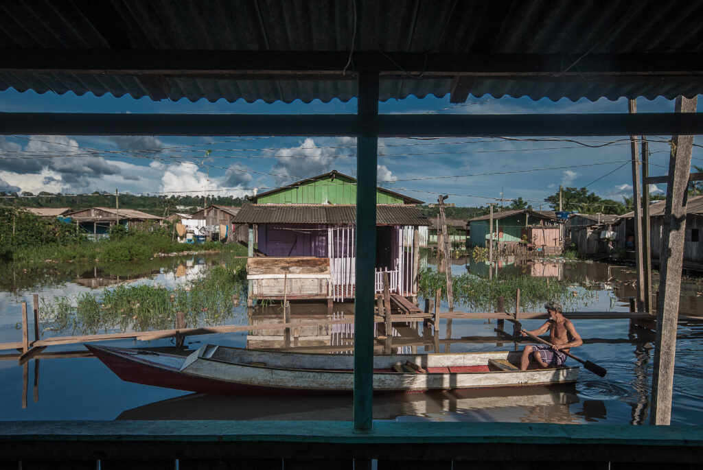 Vista de uma janela para uma rua feita de rio, com uma canoa atravessando