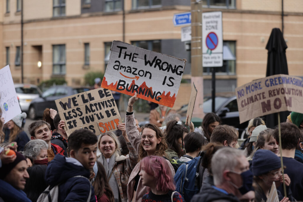Jovens seguram cartazes em inglês em uma manifestação. Um deles diz: The wrong amazon is burning