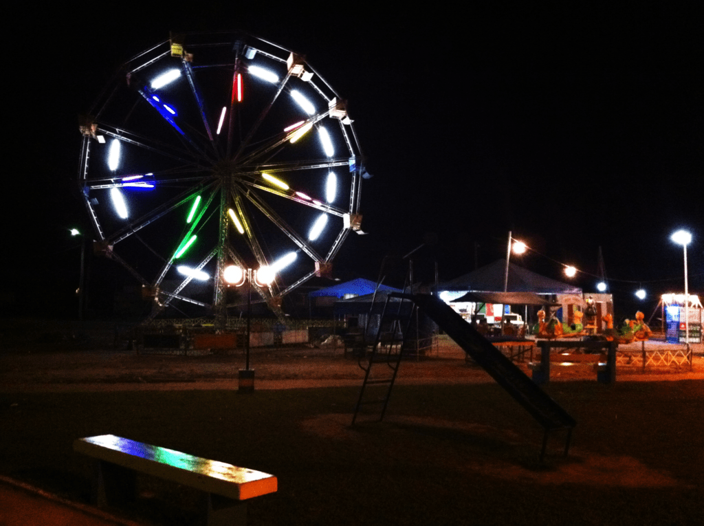 Uma roda gigante iluminado e colorida em contraste com o céu escuro