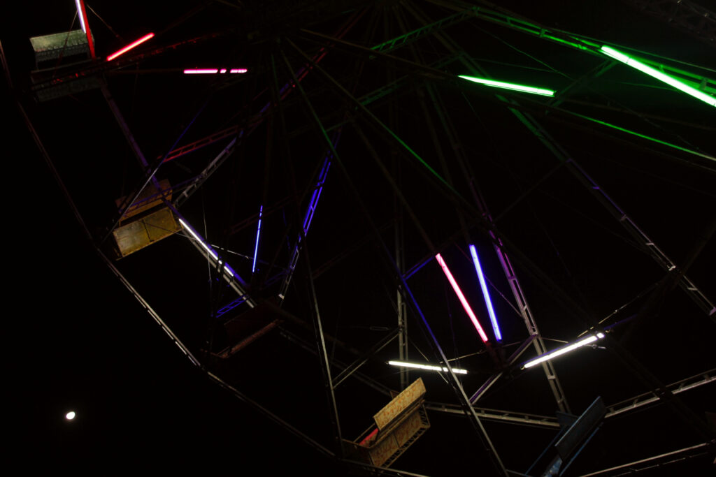 Detalhes da roda gigante por baixo, com luzes azul, verde, vermelha e branca