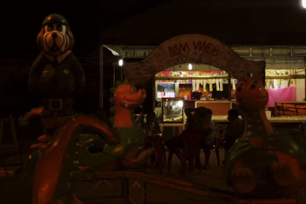 Estátuas de animais na frente de uma venda pouca iluminada com pessoas sentadas.