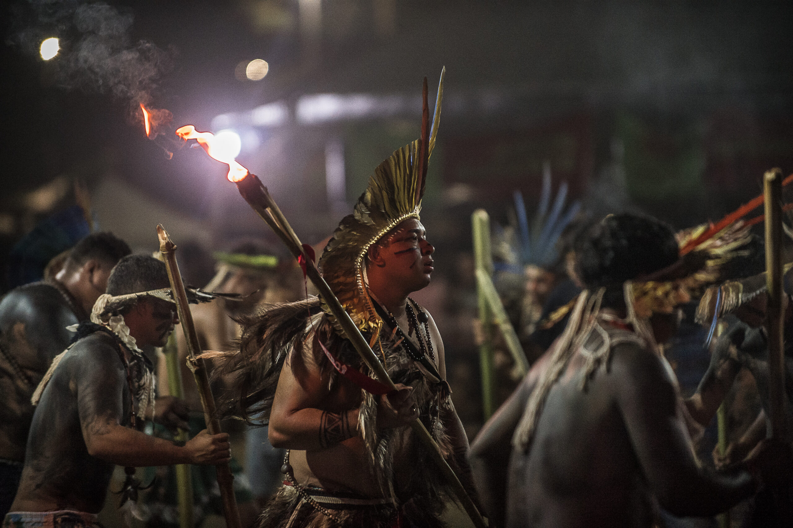 Homens indígenas fazem dança com tochas em protesto do Acampamento Terra Livre.
