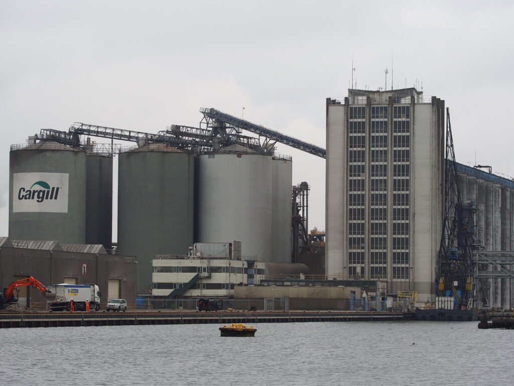 Foto de um porto da Cargill, com um rio na Frente e grandes silos ao fundo.