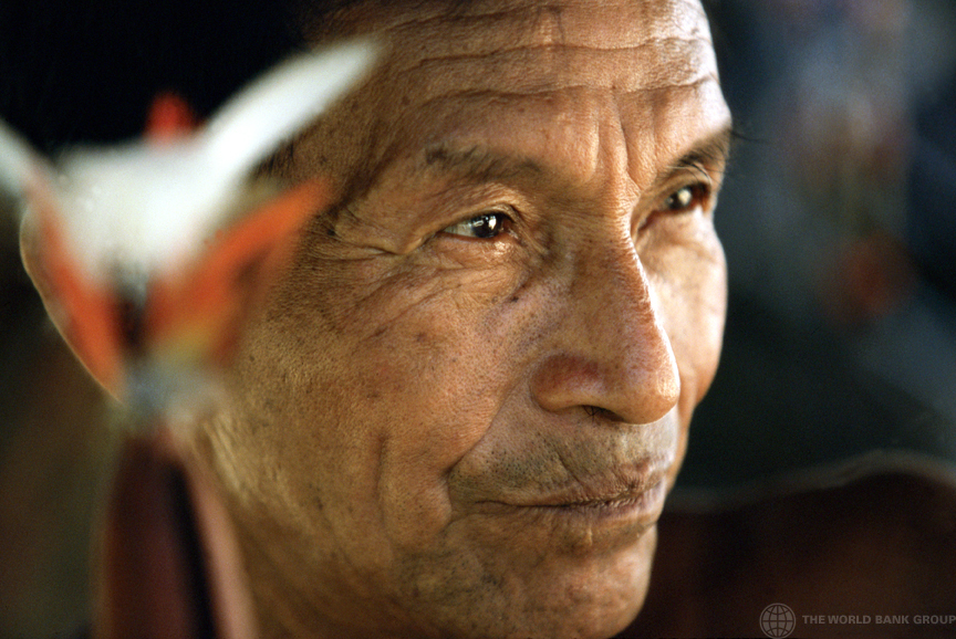Close do rosto de um homem indígena de cabelos curtos e escuros, olhos castanhos, que olha para longe.