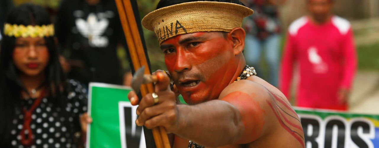 Indígena segura um arco e flecha
