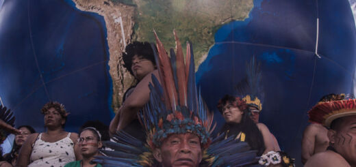 Indígenas sentados em frente ao um globo da terra