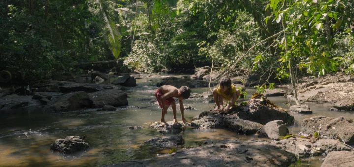 Garoto e garota indígenas brincando em um riacho.