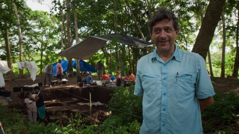 Eduardo Góes Neves, um homem branco de cabelos negros, no meio de uma escavação no meio da floresta