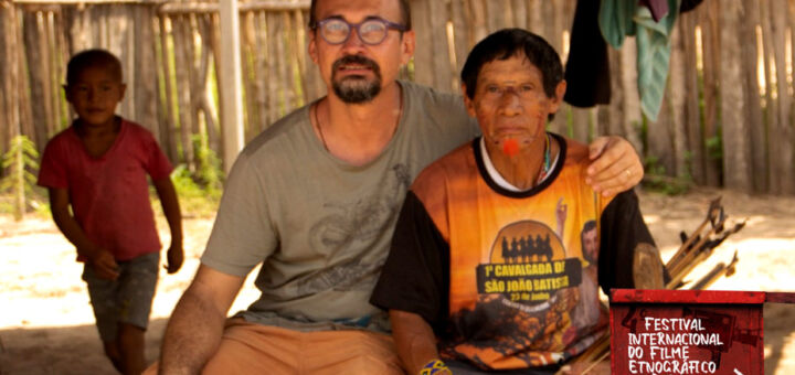 Alessandro Campos, coordenador do Festival Internacional do Filme Etnográfico do Pará, sentado ao lado de um homem indígena.
