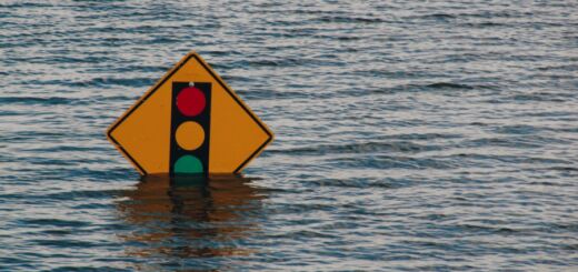 Placa de trânsito com a imagem de um semáforo quase totalmente submersa em uma enchente