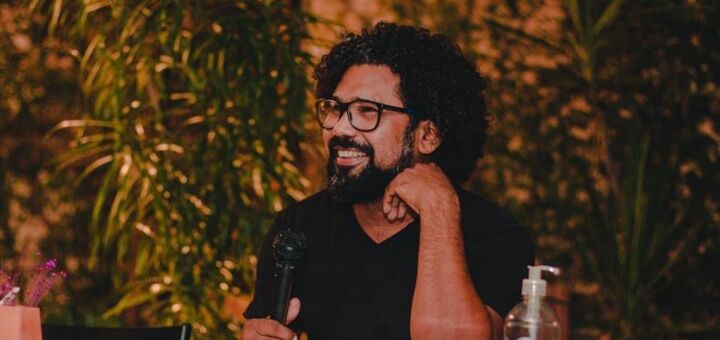 Charles Trocate sentado em uma mesa