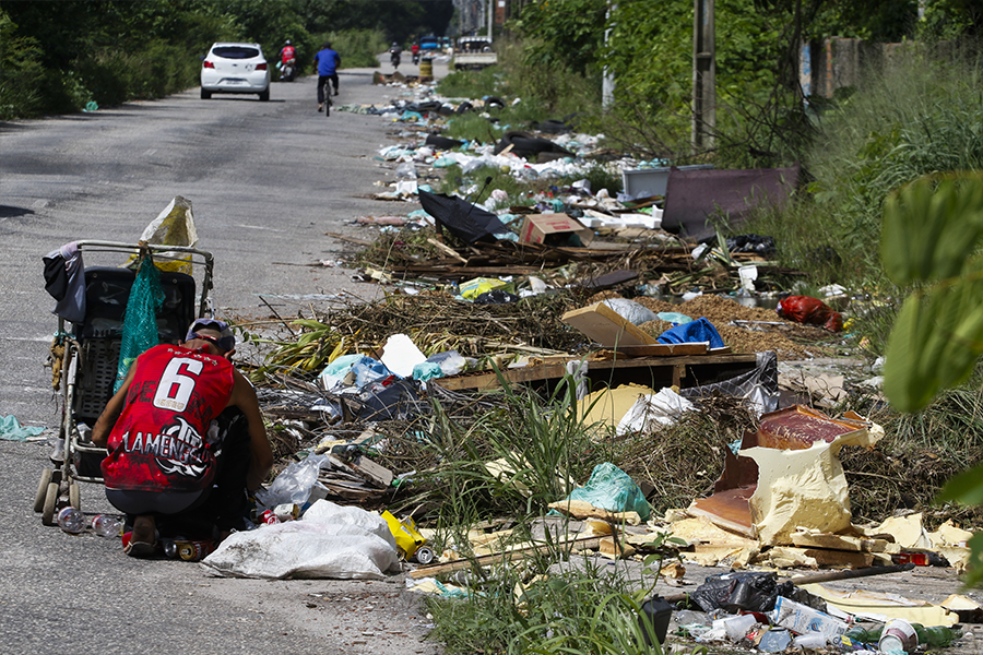 Homem abaixado próximo a monte de lixo em Belém