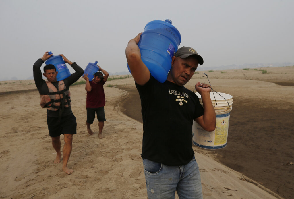 O ribeirinho e lider comunitário João Mendonça e outros ribeirinhos, carregam garrafões com água potável, para ajudar outros moradares afetados pela maior seca da história do rio Madeira, na comunidade Paraizinho, em Humaitá (AM), 08 de setembro de 2024.