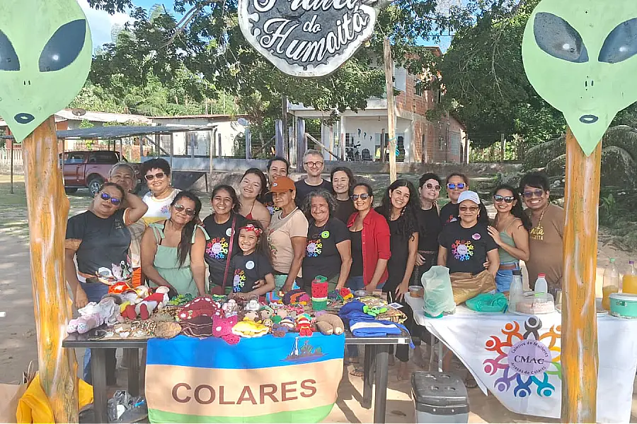 O grupo de mulheres artesãs de Colares em atividade do projeto 'Flor-e-Ser' do CAC. Através do artesanato amazônico e da economia solidária, o projeto fortalece a autonomia e a autoestima. Foto: Arquivo Pessoal de Cláudia Farias.