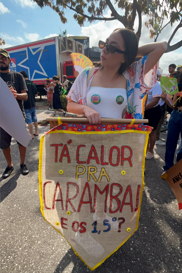 Em meio ao calor intenso de Belém, manifestante usa o bom humor para ressaltar a seriedade da crise. A faixa lembra a meta crucial das negociações da COP. Foto: Alice Palmeira/Amazônia Latitude.