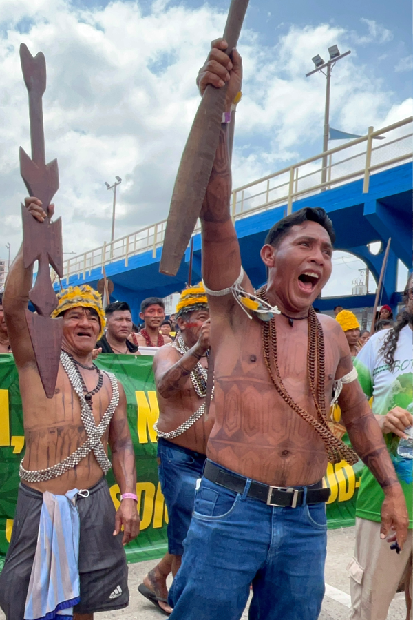 O grito de guerra pela floresta: Guerreiros indígenas levantam suas armas e soltam um grito de determinação na Marcha Mundial pelo Clima. Foto: Alice Palmeira.