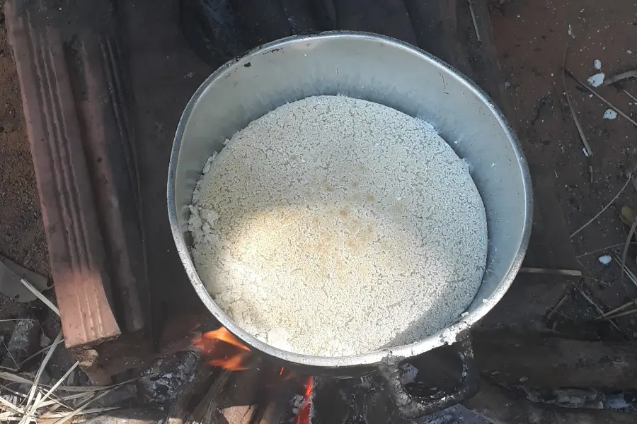 O beiju de mandioca assando lentamente sobre o fogo no chão, seguindo a técnica tradicional