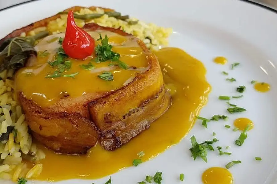 Medalhão de pirarucu bardeado com banana pacovã e finalizado com molho de tucupi cremoso. A técnica de cocção preserva a suculência da proteína de alto valor biológico, enquanto a banana agrega textura e nutrientes essenciais à composição. Foto: Sigrid Ruiz/Amazônia Latitude.