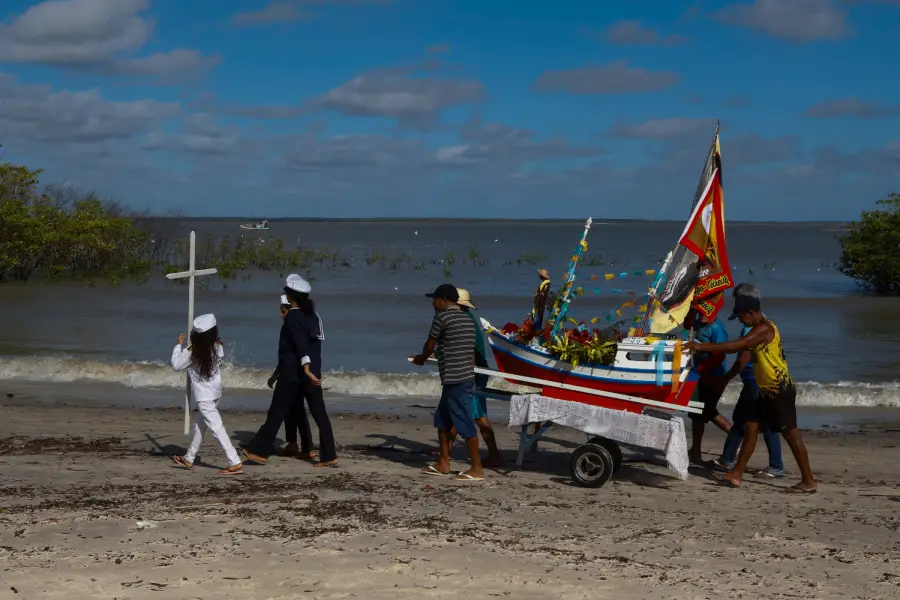 Devotos caminham em cortejo pela faixa de areia carregando o andor ornamentado com a imagem de São Pedro. A caminhada margeia a praia e os manguezais, conectando os altares flutuantes ao chão firme da comunidade. Foto: Oswaldo Forte/Amazônia Latitude.