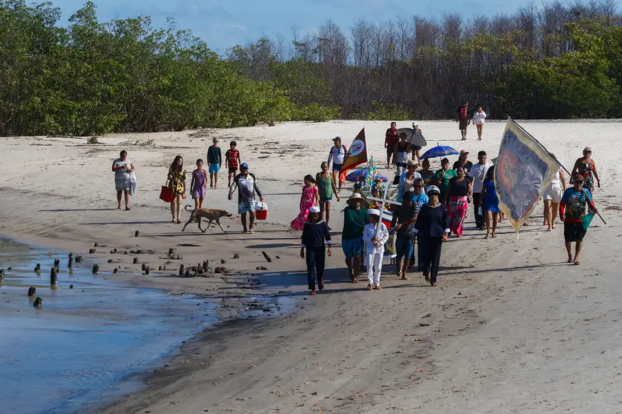 Sob o estandarte e guiados por símbolos da marujada, moradores e veranistas acompanham a imagem pela costa da ilha. O rito estende-se para além das águas, arrastando passos firmes sobre a areia úmida do litoral paraense. Foto: Oswaldo Forte/Amazônia Latitude.