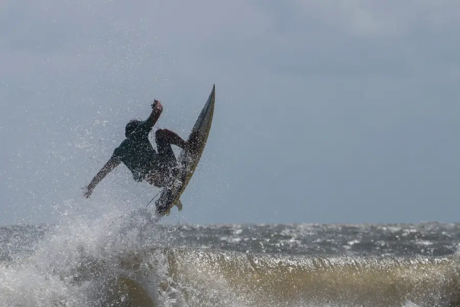 Um surfista executa uma manobra aérea precisa, rompendo a crista de uma onda barrenta, típica das águas ricas em sedimentos da região costeira paraense. Foto: Oswaldo Forte/Amazônia Latitude.