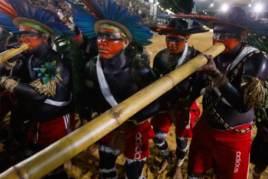 Homens indígenas entoam instrumentos tradicionais de sopro em performance ritual na arena do evento. Foto: Oswaldo Forte / Amazônia Latitude.