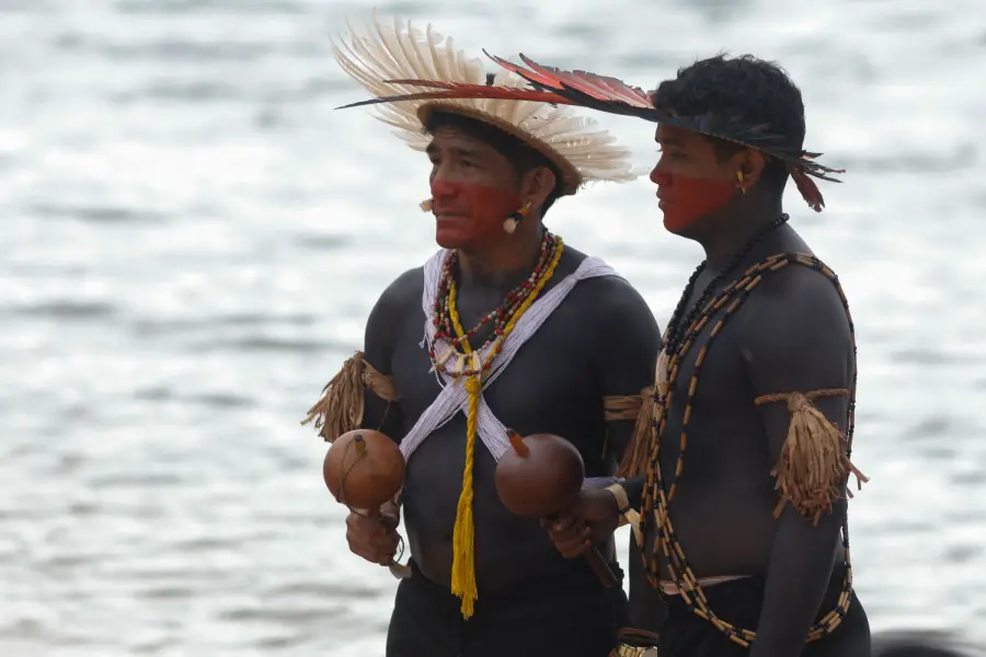 Homens ornamentados com maracás e pinturas corporais postam-se à beira do rio Xingu. Foto: Oswaldo Forte / Amazônia Latitude.