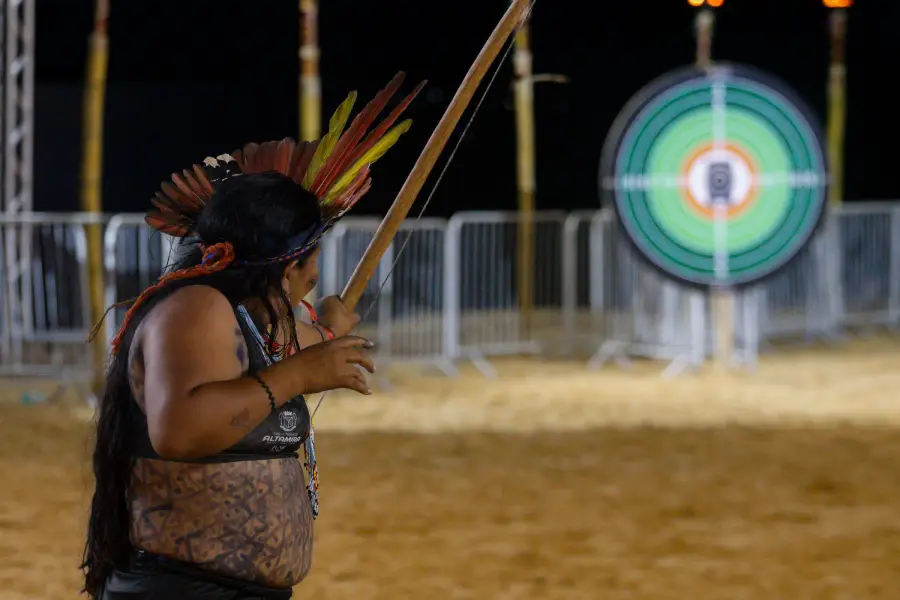 Na arena noturna, competidora projeta o disparo do arco e flecha em direção ao alvo. Foto: Oswaldo Forte / Amazônia Latitude.