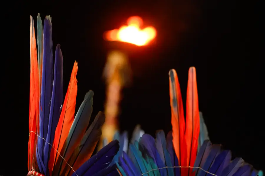 Plumas coloridas emolduram a tocha acesa na arena, simbolizando a união e a celebração dos povos do Xingu. Foto: Oswaldo Forte / Amazônia Latitude.