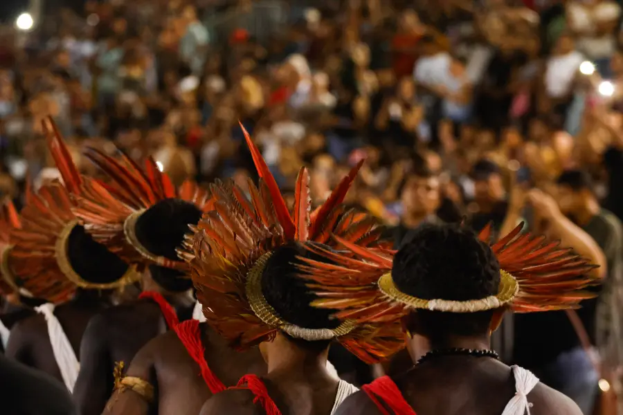 Plumas coloridas emolduram a tocha acesa na arena, simbolizando a união e a celebração dos povos do Xingu. Foto: Oswaldo Forte / Amazônia Latitude.