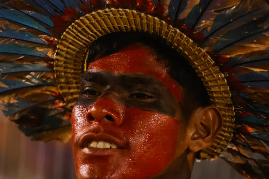 Retrato em close destaca a pintura tradicional em urucum e o cocar ornamental de participante dos Jogos. Foto: Oswaldo Forte / Amazônia Latitude.