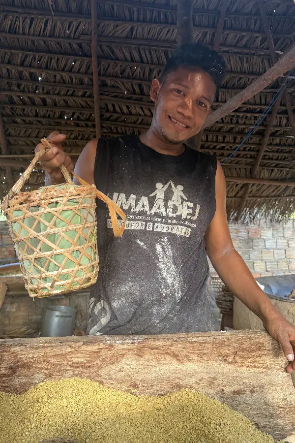 Mandiocultor segura cesto artesanal tradicional trançado em palha e forrado com folha verde diante da gamela de farinha fresca. Foto: Miguel Picanço/Amazônia Latitude.