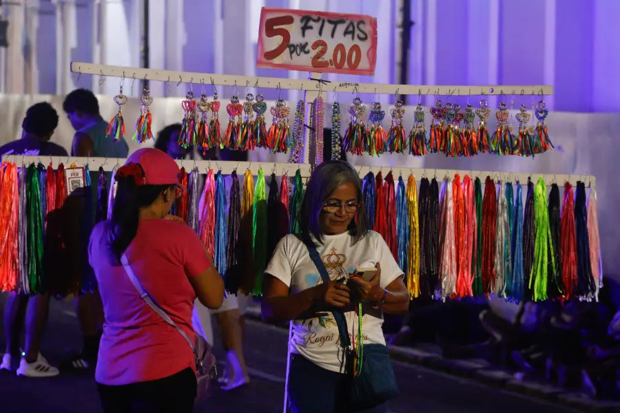 Nas cores e na simplicidade das bancas de rua, as fitas coloridas balançam ao vento carregando os pedidos, as promessas e a esperança de cada romeiro que passa. Foto: Oswaldo Forte/Amazônia Latitude.