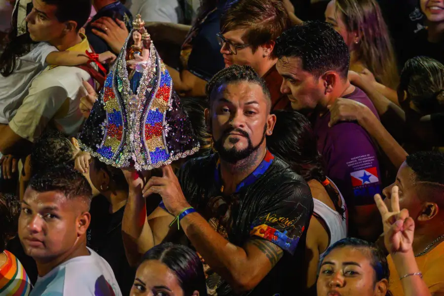 No coração da Trasladação, a fé veste-se de inclusão e afeto: um devoto ergue a imagem sagrada envolta em um manto inspirado no símbolo da neurodiversidade, lembrando que o Círio acolhe todas as lutas, cores e esperanças do povo. Foto: Oswaldo Forte/Amazônia Latitude.