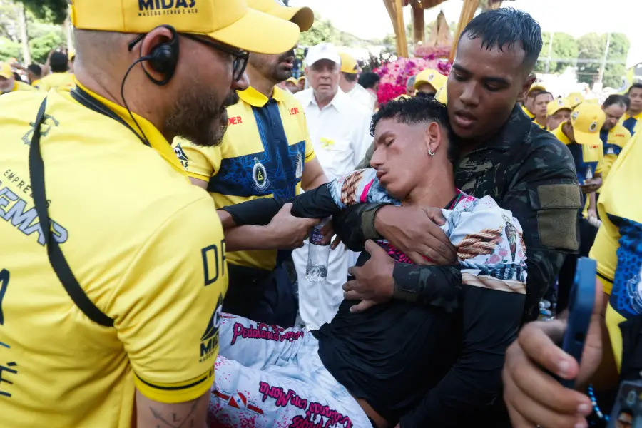 Romeiro é amparado e carregado com cuidado por membros da segurança e da Guarda de Nazaré, traduzindo o esforço físico que acompanha a fé. Foto: Oswaldo Forte/Amazônia Latitude.